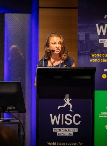 The image is of Victoria Kahn presenting at the Women in Sport Congress. 
